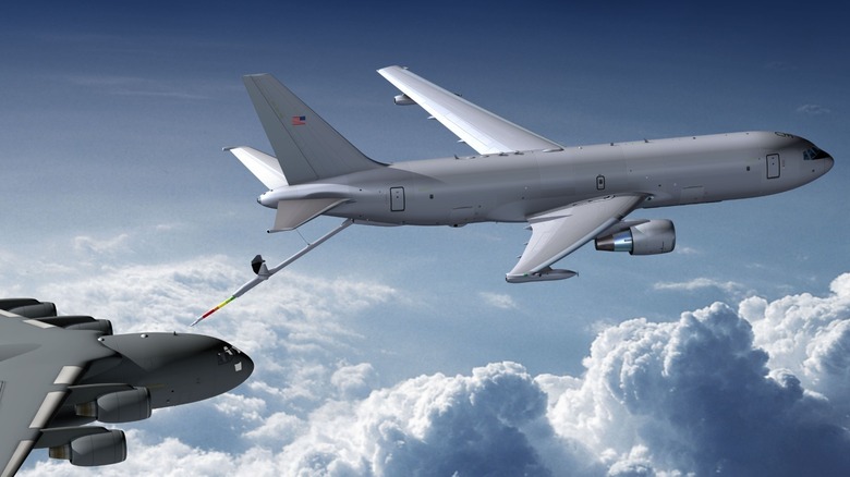 Large gray plane refueling a darker grey plane in air against a cloudy sky.
