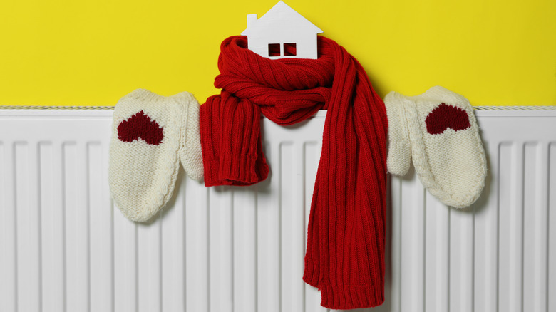 Symbolic image showing a model house wrapped in a scarf sitting on a radiator