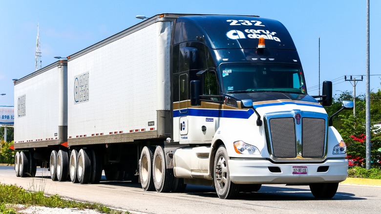 A two-tone black and white Kenworth T680 pulling a double trailer