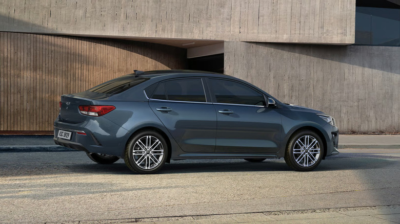 Kia Rio from the side next to industrial building