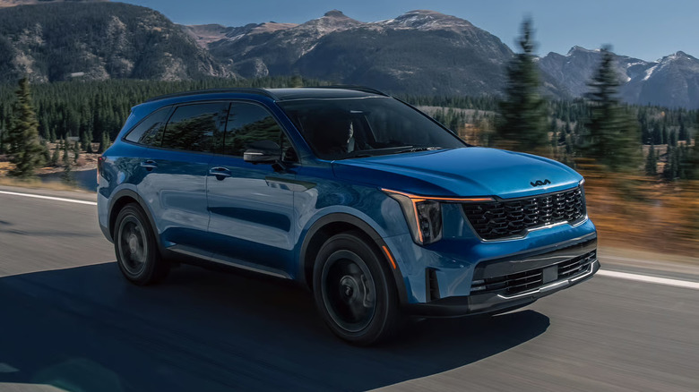 A blue 2027 Kia Sorento Hybrid on a paved road in the mountains