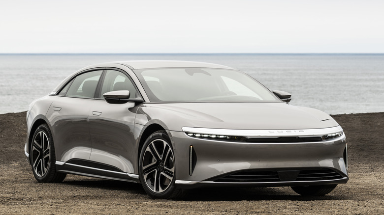 A front 3/4 view of Lucid Air on a beach with the ocean in the background