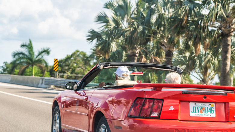 Couple driving down Florida highway in convertible