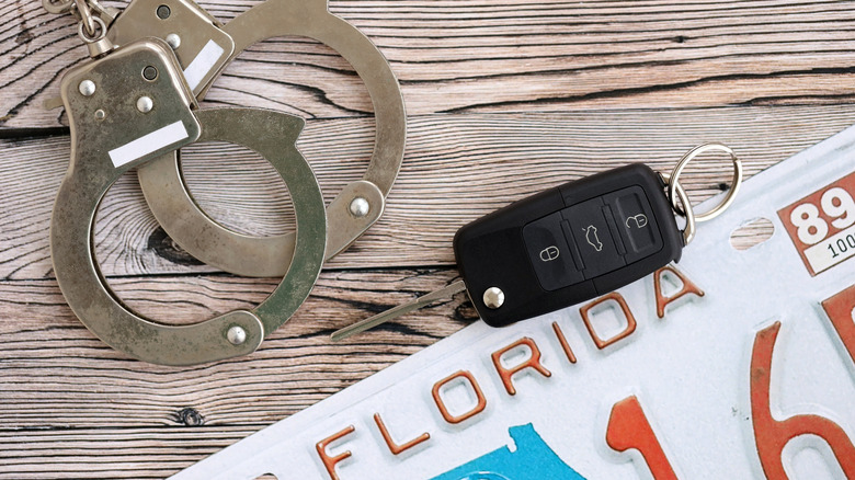 Handcuffs and car key next to Florida license plate