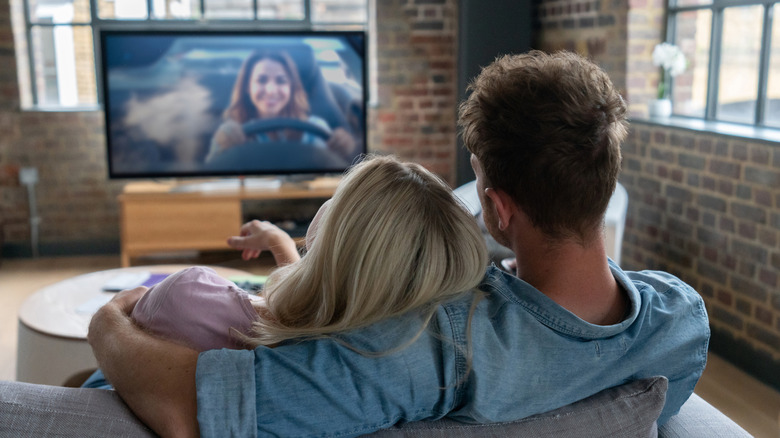 Man and woman sitting on a sofa watching TV