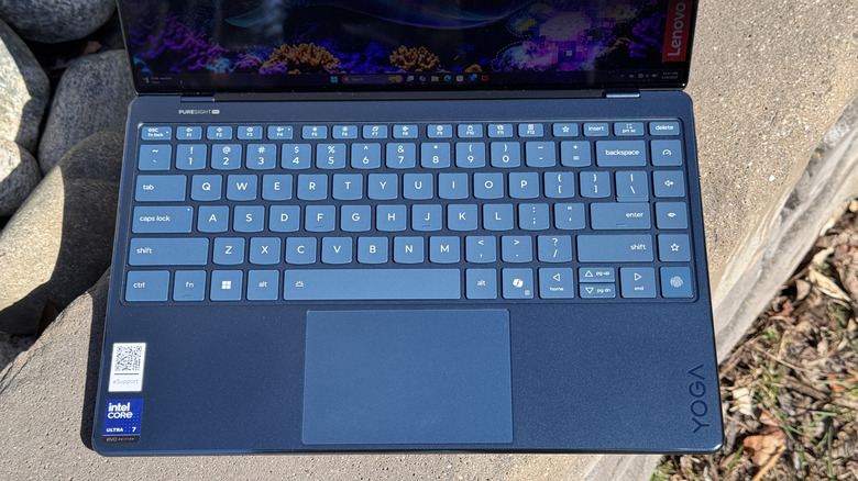 The Lenovo Yoga Slim 9i 14 Gen 10 keyboard and Trackpad on a concrete ledge.
