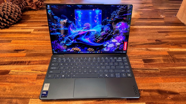 The Lenovo Yoga Slim 9i 14 Gen 10 on a wooden counter top with pine cones in the back left of the image.