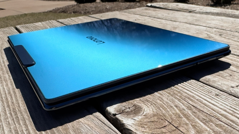 The Lenovo Yoga Slim 9i 14 Gen 10 with its reflective lid closed on a wood picnic table..