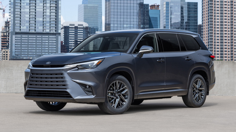 Black 2026 Lexus TX parked with city skyline in the background.