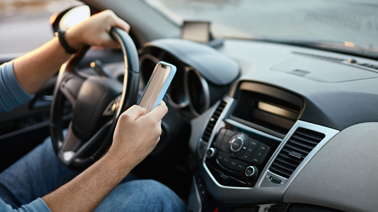 man using phone while driving car