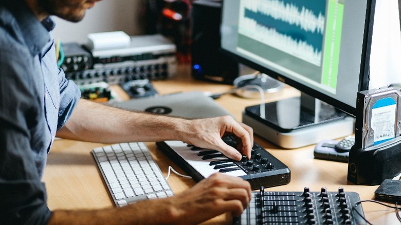 Music Producer behind his desk working on a MID controller