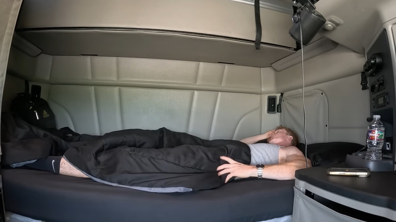 driver resting in a spacious semi-truck sleeper unit