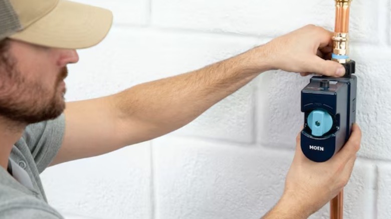 Person installing Moen Flo Smart Water Monitor