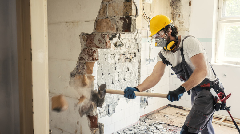 construction worker demolishing wall with sledgehammer