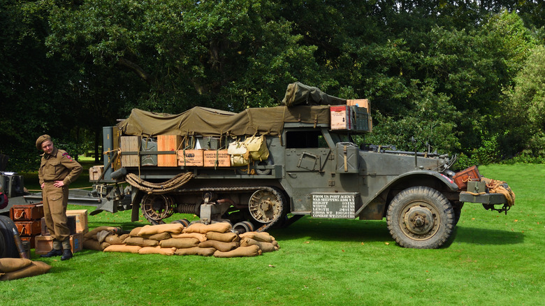 Vintage M3 Half Track with soldier standing to the left during a 2023 re-enactment