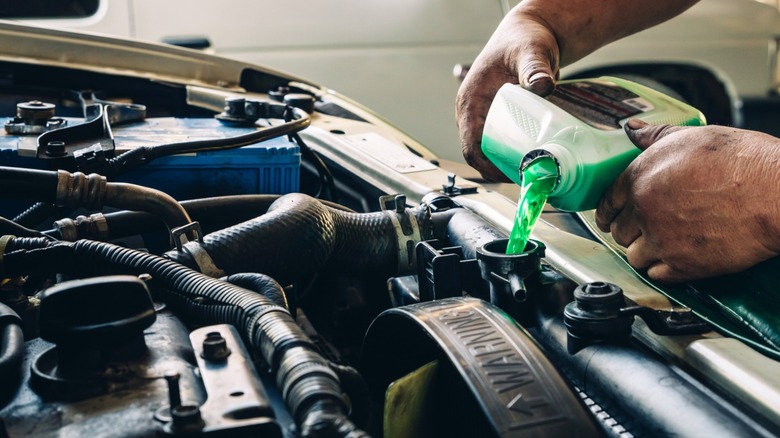 Person pouring antifreeze into engine