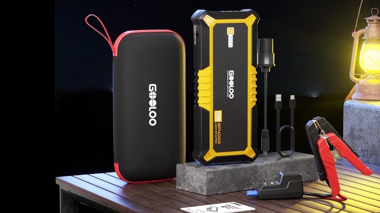 a jump starter and accessories on a table with a lantern
