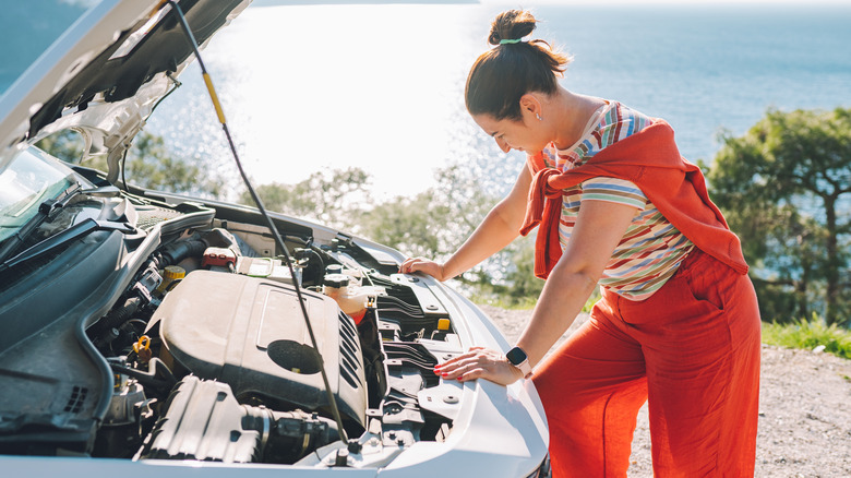 person looking under the hood of their car
