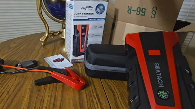 A jump starter on a table with packaging and clamps