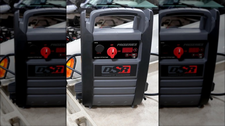 A jump starter on a cart near a vehicle