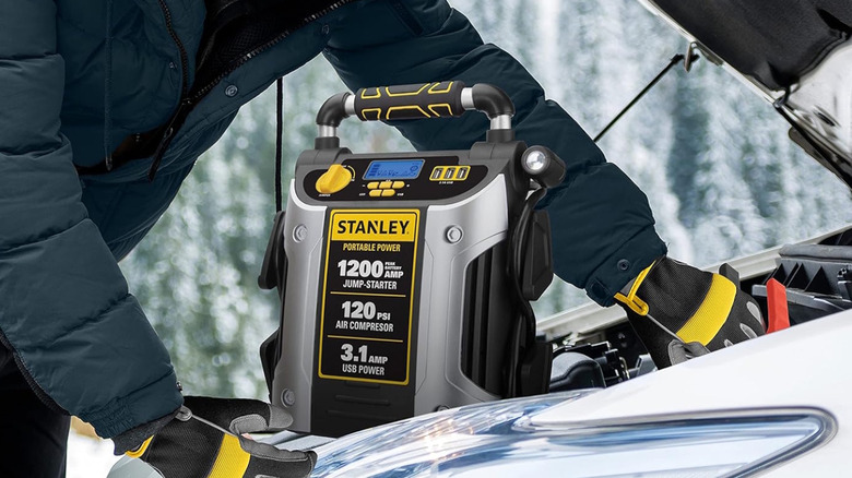 jump starter resting under the hood of a vehicle
