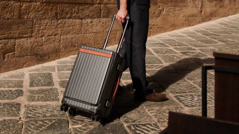 A person pulling a Carl Friedrick suitcase behind them
