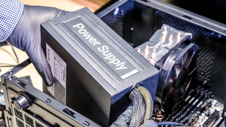 A technician installing a power supply in a PC