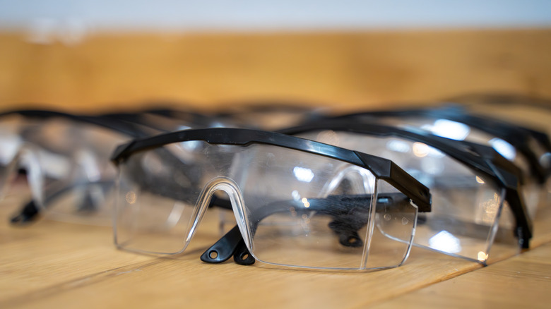 Many similar safety glasses lined up on a table.