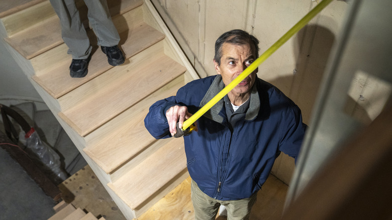 A person measuring out from a corner in their basement