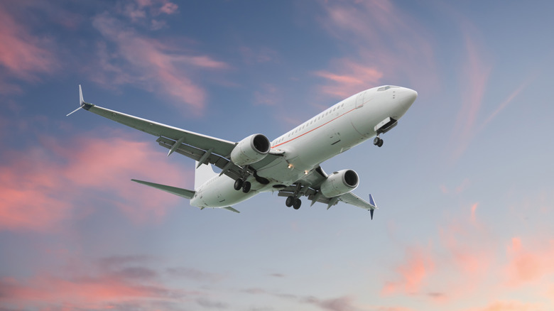 Airplane flying in beautiful sky with clouds at sunset
