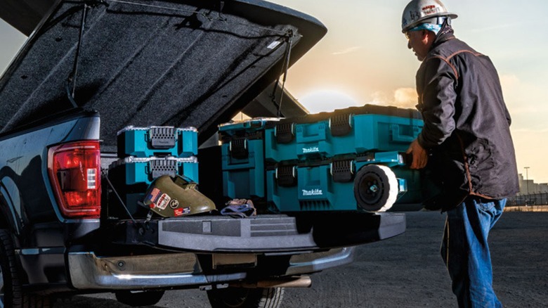 Person loading Makita MakTrak boxes onto a pickup truck