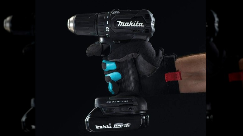 man holding Makita drill with a black background