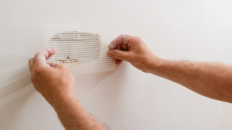 Person applying drywall patch