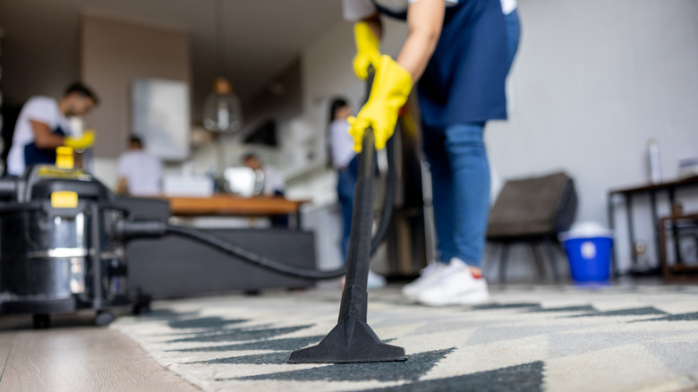 floor vac being used on carpet with cleaners in background