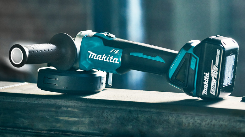 A Makita cordless 4-1/2-inch cut-off/angle grinder resting on a beam