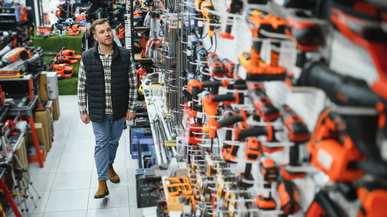 A man looking at tools on display on a pegboard in a store.