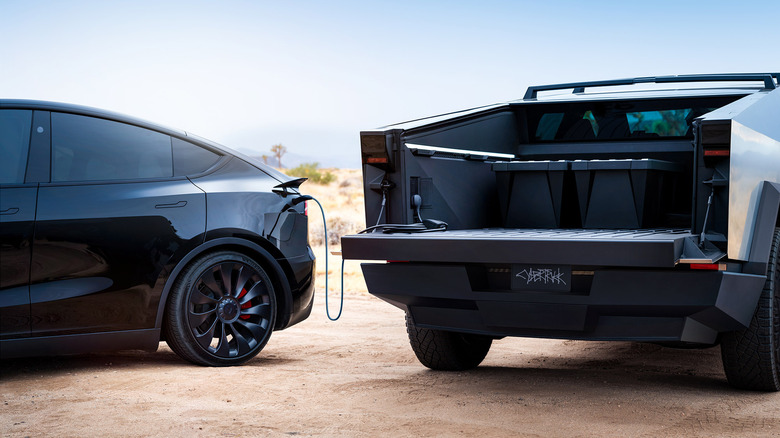 Rear view of Tesla Cybertruck charging black Tesla Model Y.