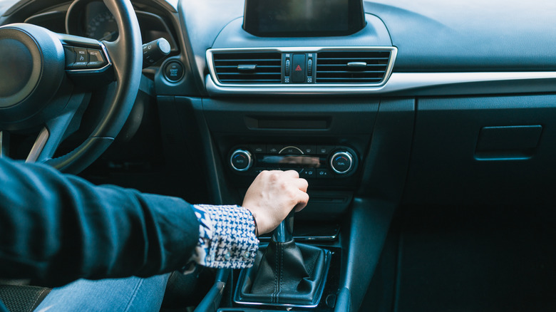 Person driving manual transmission car, shifting with right hand