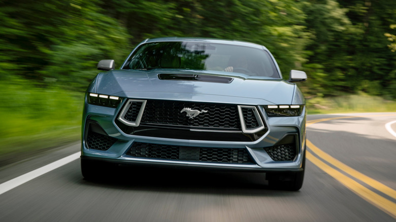 Ford Mustang driving towards the camera with pony badge prominently visible