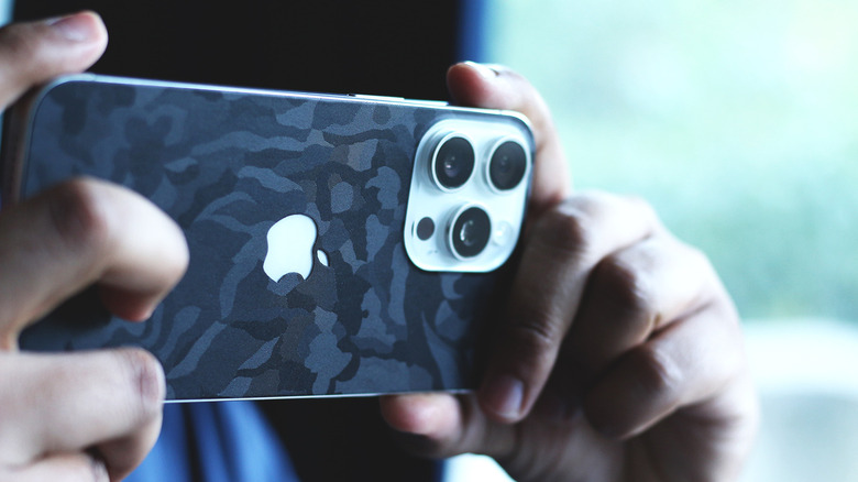 Person recording a video with a Pro iPhone model with a camo skin