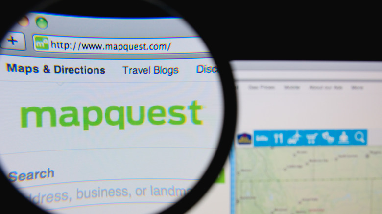 Person using magnifying glass to highlight MapQuest logo online