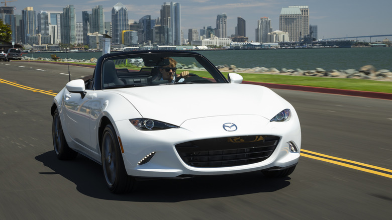 Front view of white Mazda MX-5 Miata driving near harbor.