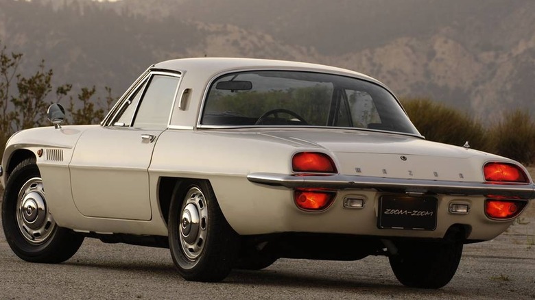 Mazda Series I Cosmo 110S import parked on mountainside hard shoulder, rear-left view