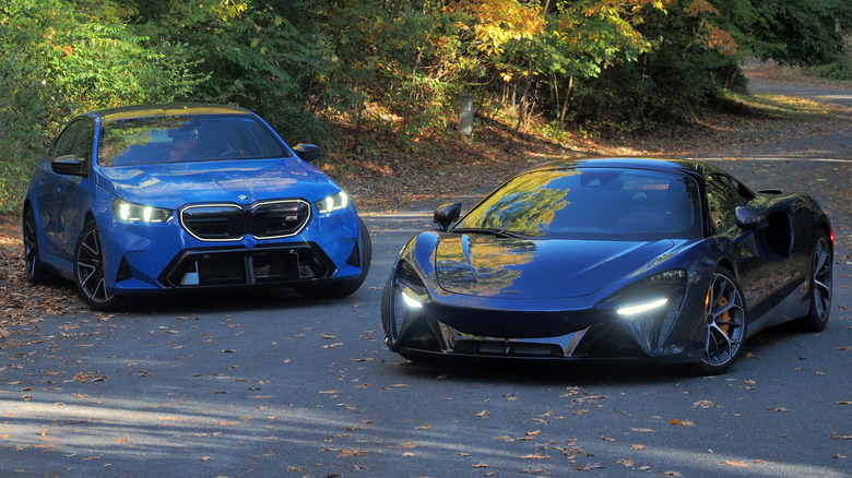 BMW M5 and McLaren Artura parked in a wooded road