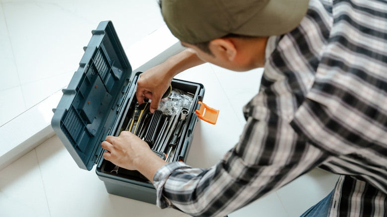 Man sorting through blue gray tool box