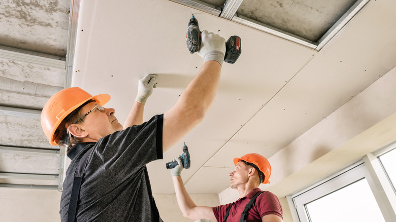 people attaching drywall to joists