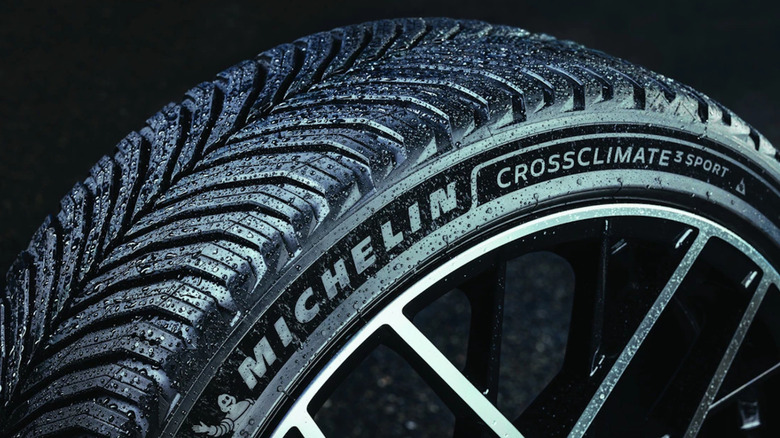 Close-up of a wet Michelin CrossClimate 3 tire on a black background.