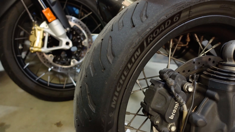 The lettering on the sidewall of the Michelin Road 6 tire, a different motorcycle wheel in the background