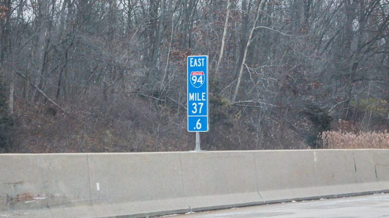 Blue mile marker sign on side of highway