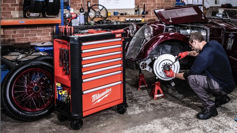 Mechanic working beside a Milwaukee Toolguard 30-inch 7-Drawer Steel Storage Rolling Cabinet